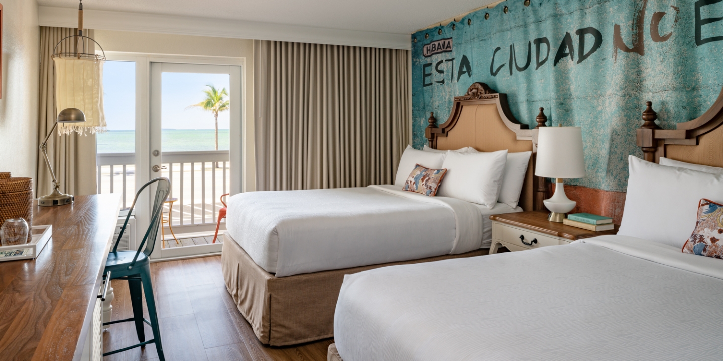 Guest room with two beds, balcony, and ocean view at Havana Cabana