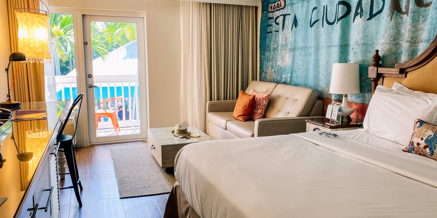 Two twin queen-sized beds overlooking a wooden desk area next to the balcony