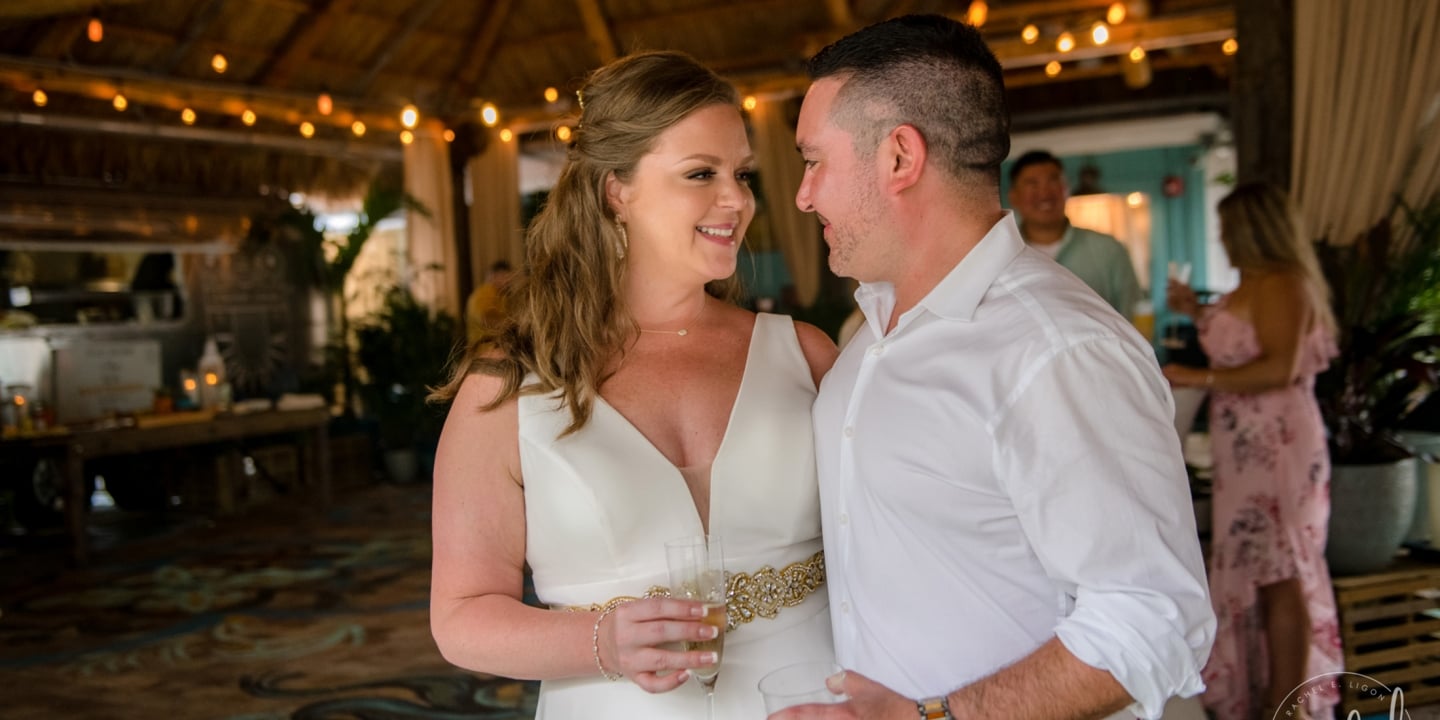 Bride and groom gazing at each other while holding their drinks