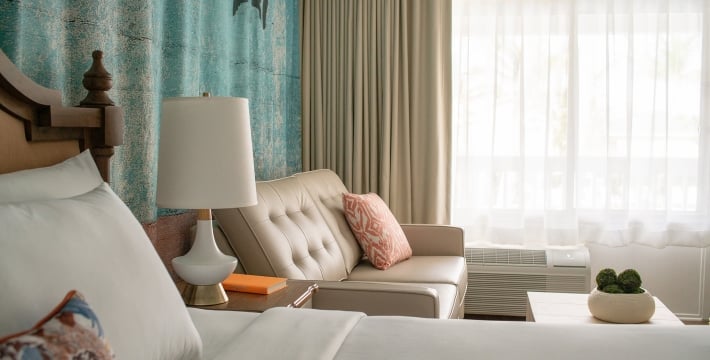 A king bedroom with a night table, couch and ottoman.