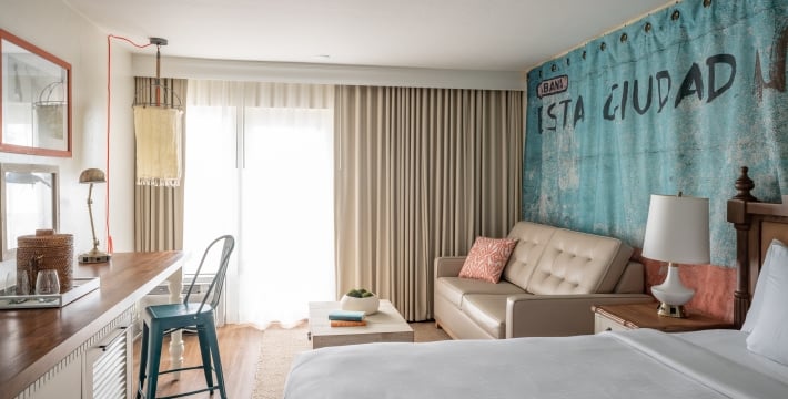 Interior of a king bedroom at Havana Cabana with a couch, ottoman and table.